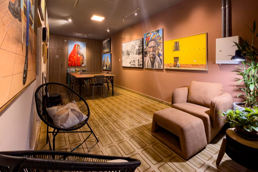 Sala de espera da galeria com poltronas e obras emolduradas